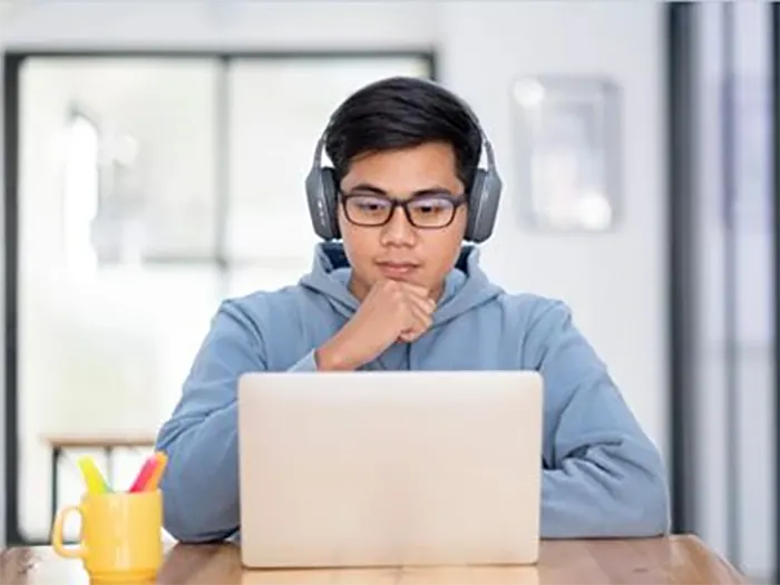 Xjq6Dyoungasianstudentmanwearingheadsetandlookingatlaptopdisplayforlearningonlinecourse 1